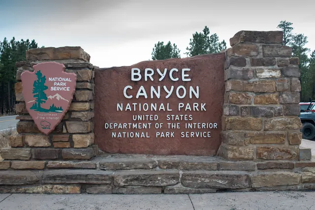 A stone monument sign of red rock reading Bryce Canyon National Park Department of the Interior